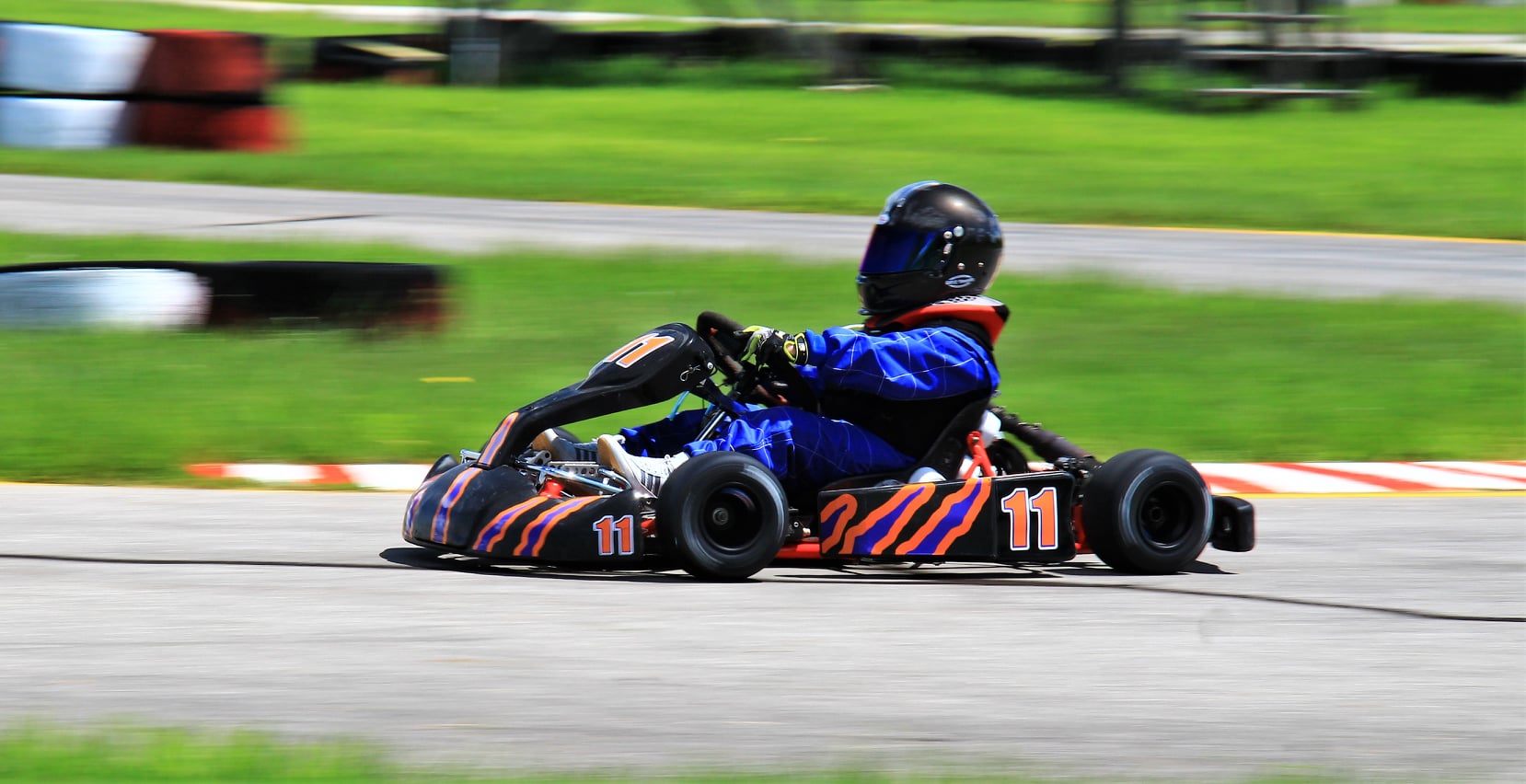 Young Ryan Johnston racing #11 go-kart at speed in blue suit during early career