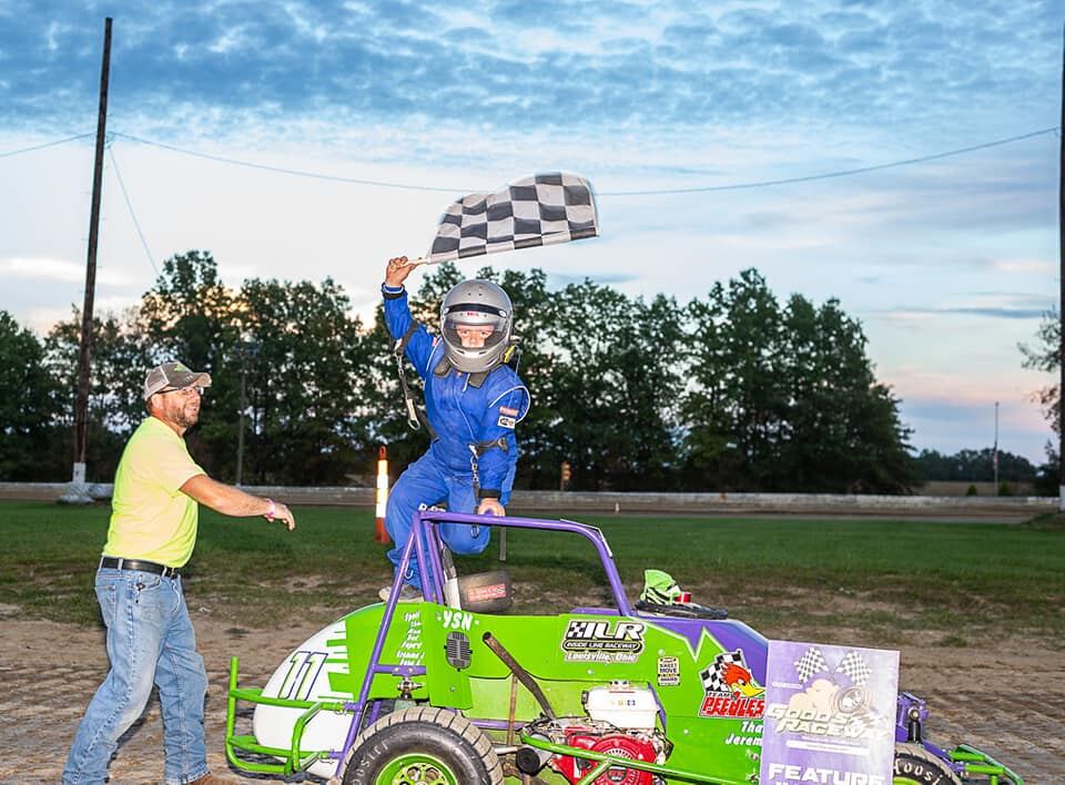 Ryan Johnston celebrating with checkered flag on top of #11 EconoMod at dusk